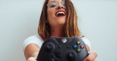 Woman holding a black Xbox One controller and laughing