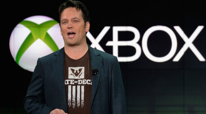 Phil Spencer wearing a State of Decay t-shirt in front of the xbox 360 era logo